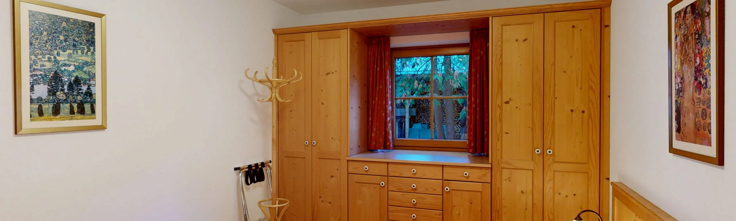 Ein Zimmer mit Holzregalen und Fenstern, Bilder an der Wand.