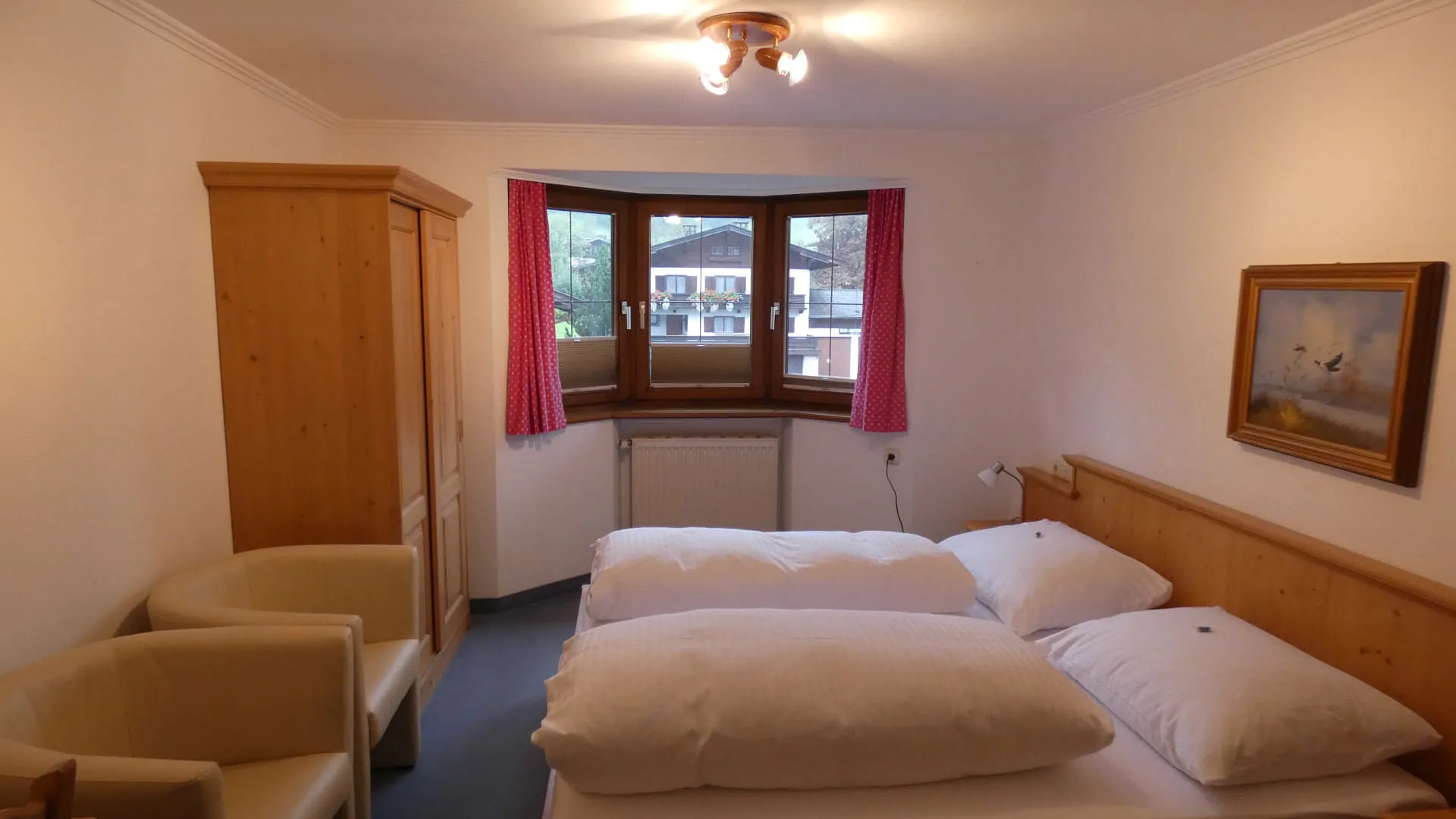 Helle, einfache Zimmer mit Doppelbett und zwei Stühlen.