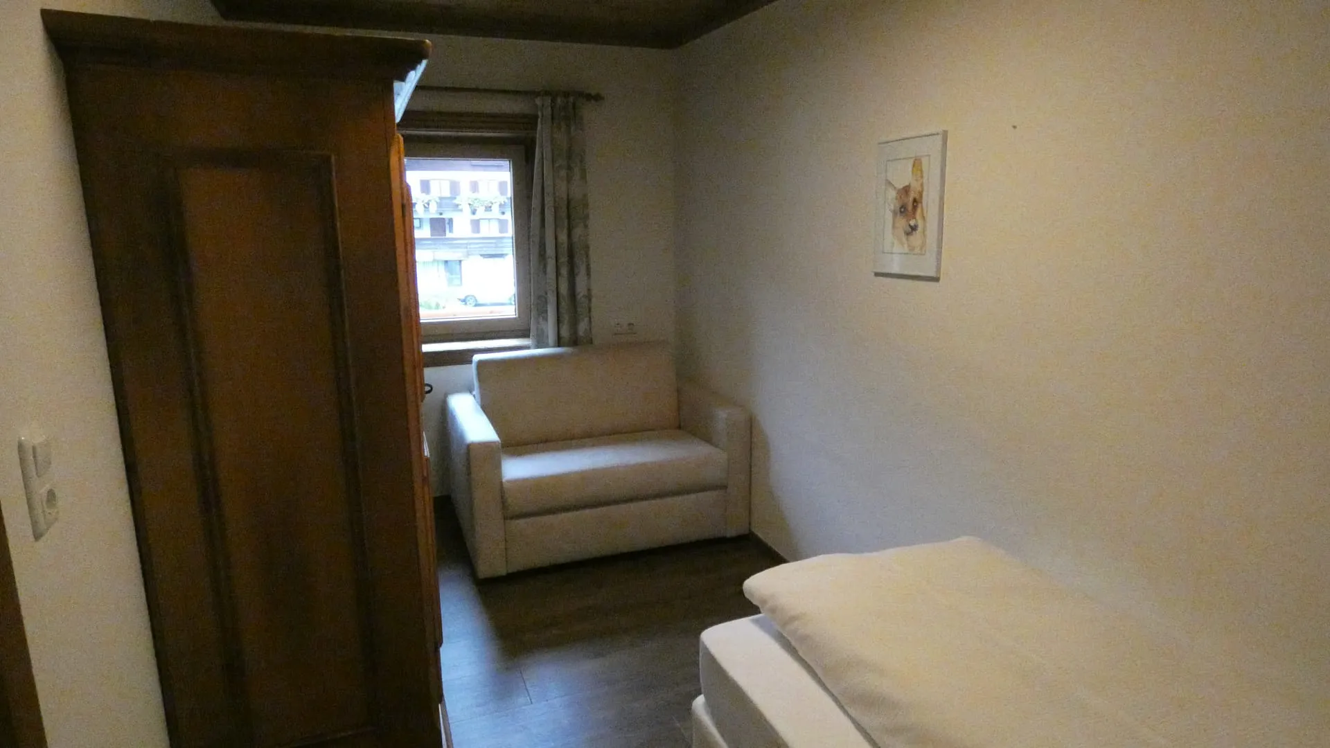 Zimmer mit Bett, Sessel und Fenster, hell und modern gestaltet.