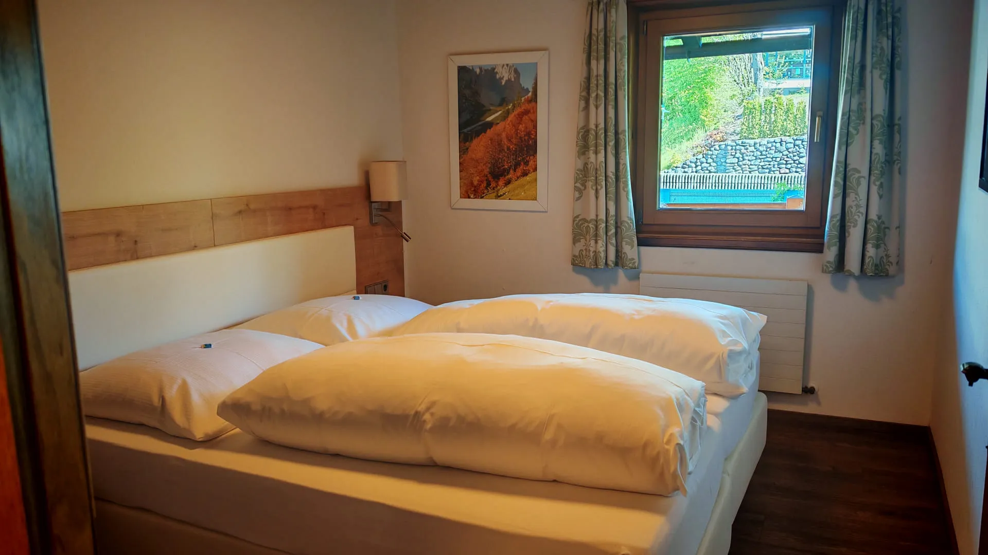 Helles Schlafzimmer mit Doppelbett und Fensterblick nach draußen