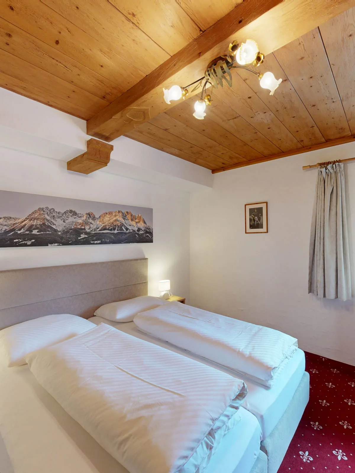 Schlafzimmer mit zwei Betten, Holzdecke und Fenster mit Aussicht
