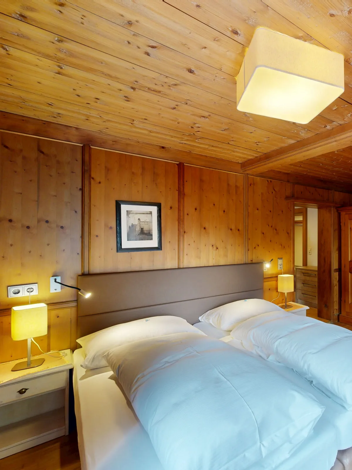 Schlafzimmer mit zwei Betten, Holzdecke und Möbeln aus Holz