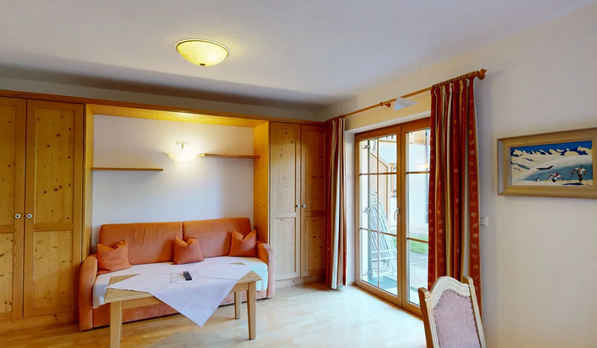 Helles Wohnzimmer mit Sofa, Tisch und Zugang zum Balkon