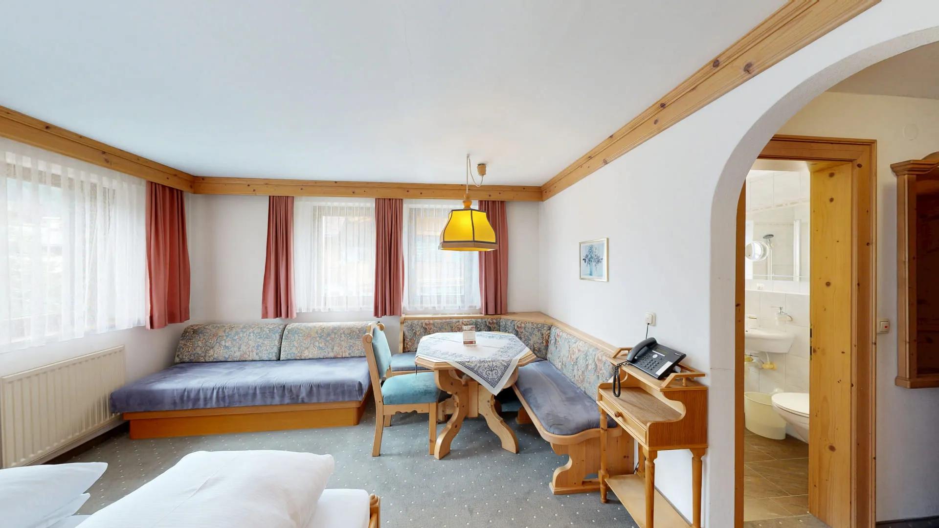 Helle Hotelzimmer mit Couch, Tisch und angrenzendem Badezimmer