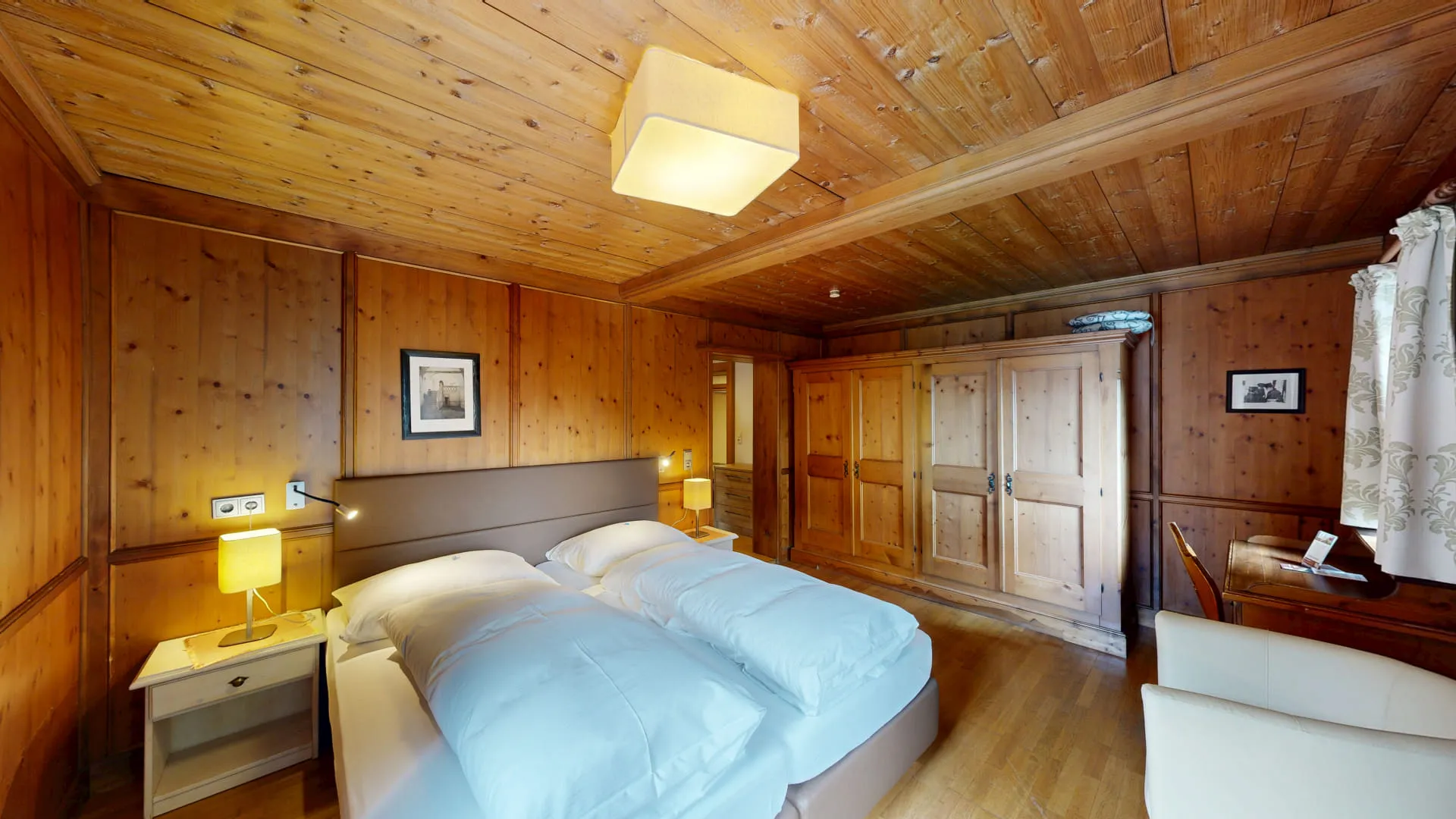 Helles, rustikales Schlafzimmer mit Holzdecke, zwei Betten und einem Kleiderschrank