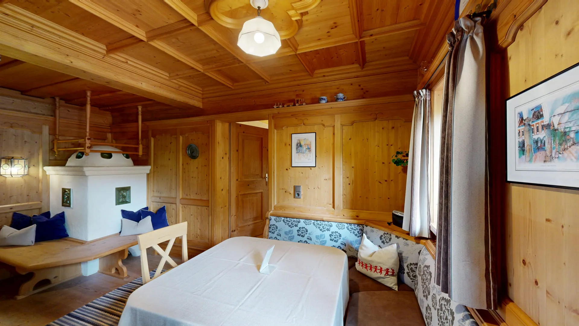 Gemütlicher Raum mit Holzvertäfelung, Kamin, Tisch und Sitzgelegenheiten.