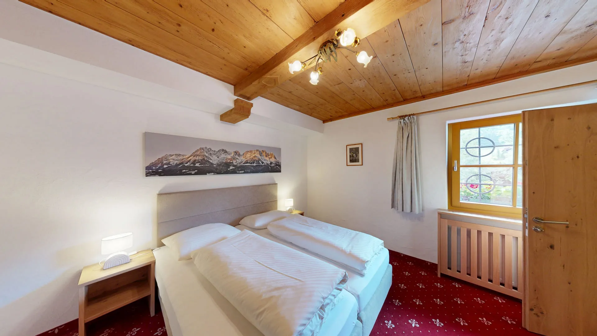 Helle Hotelzimmer mit zwei Betten, Holzdecke und Fensterblick.