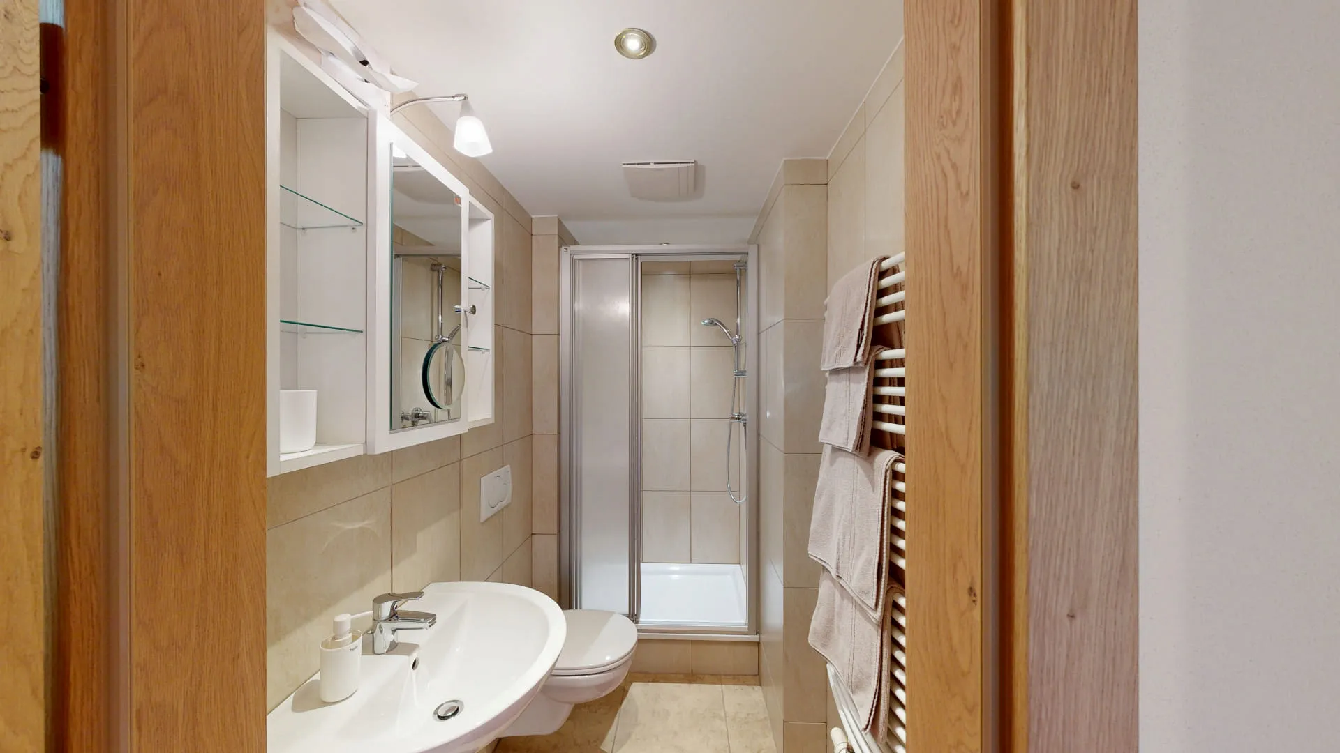 Badezimmer mit Dusche, Waschbecken und Handtüchern an der Wand
