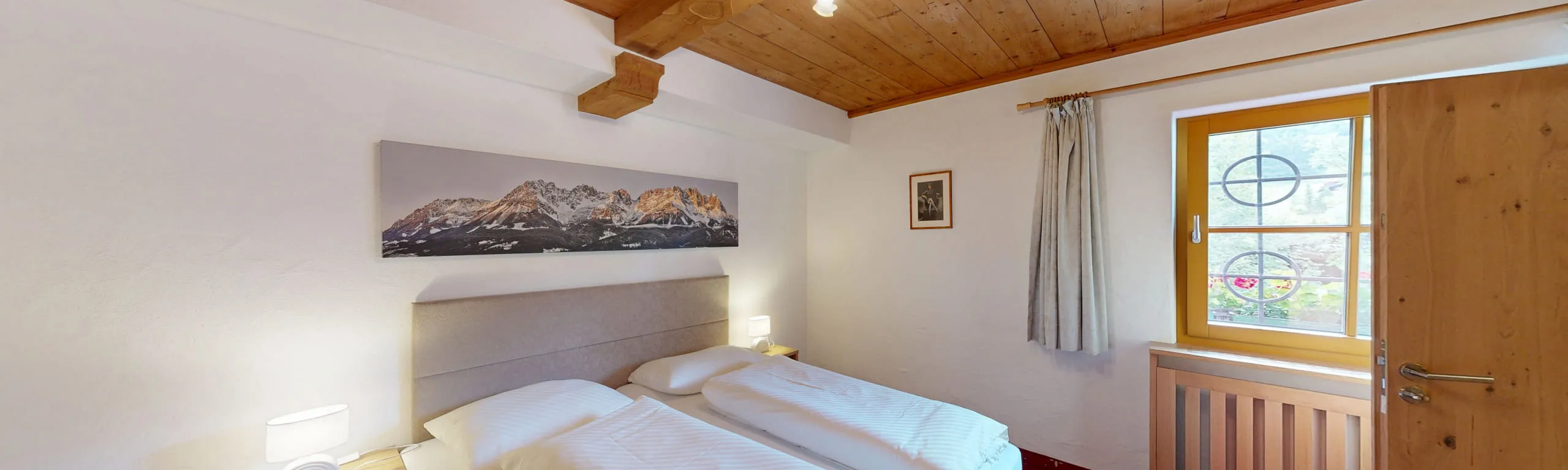 Helles Schlafzimmer mit zwei Betten, Fenster und Bergmalerei an der Wand.